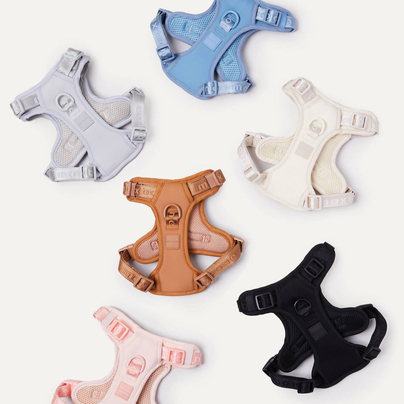 Six different colored dog harnesses. Blue, white, gray, camel, black, pink.