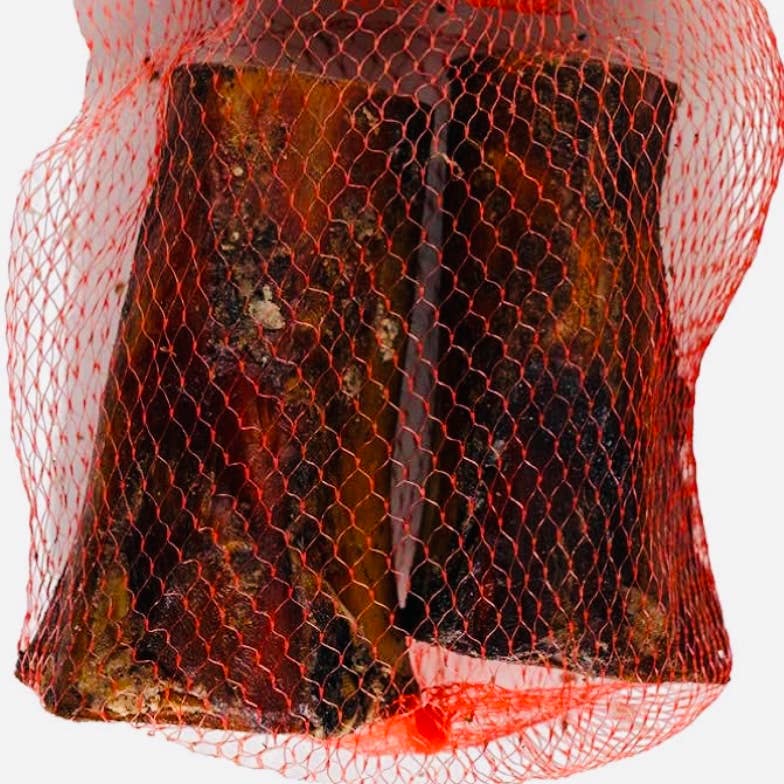 Red mesh bag containing grass fed marrow bones on a white background.