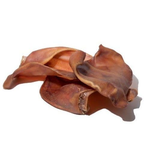 A pile of 3 pig ear dog chews on a white background.