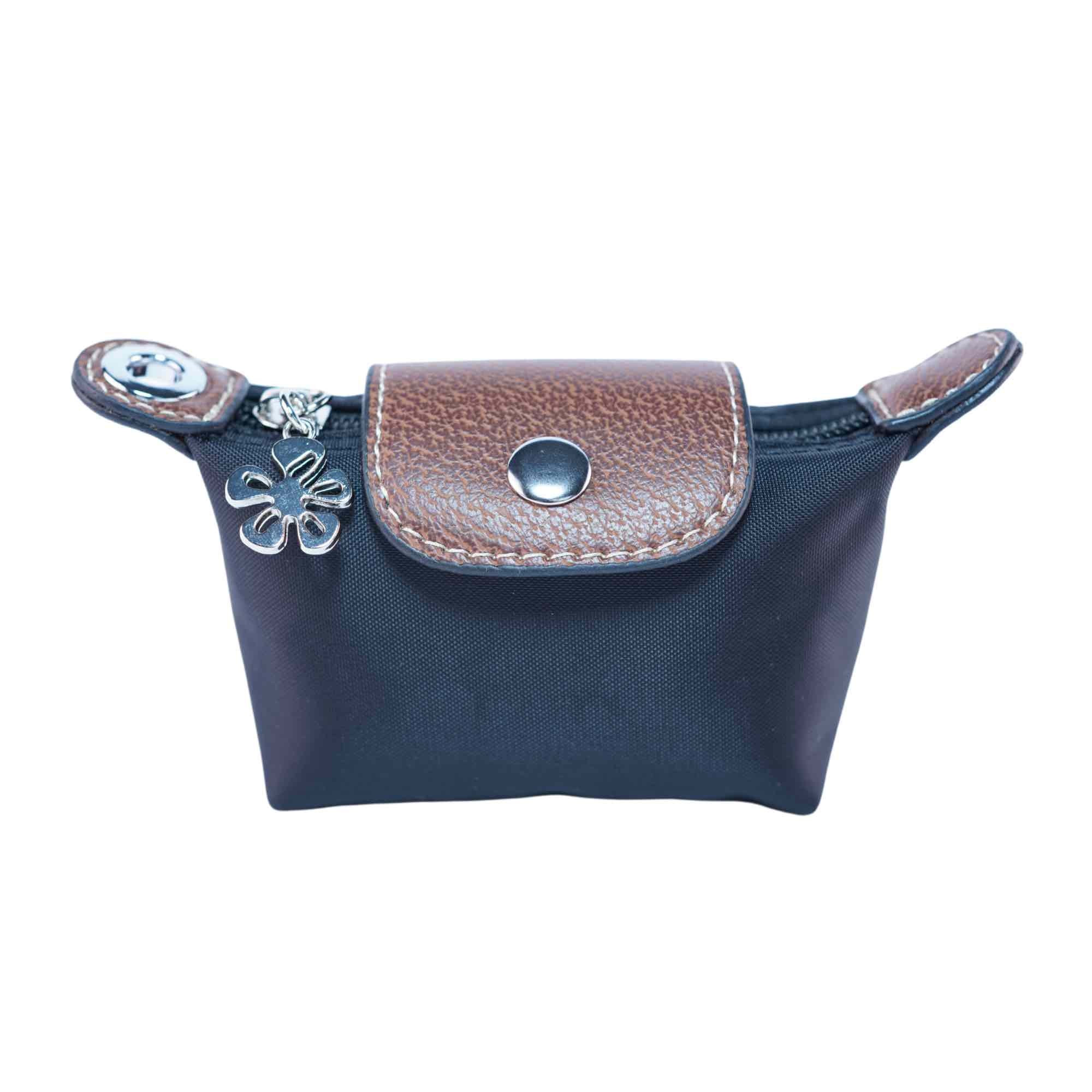 Small black dog waste bag pouch with brown leather flap and flower charm on a white background.