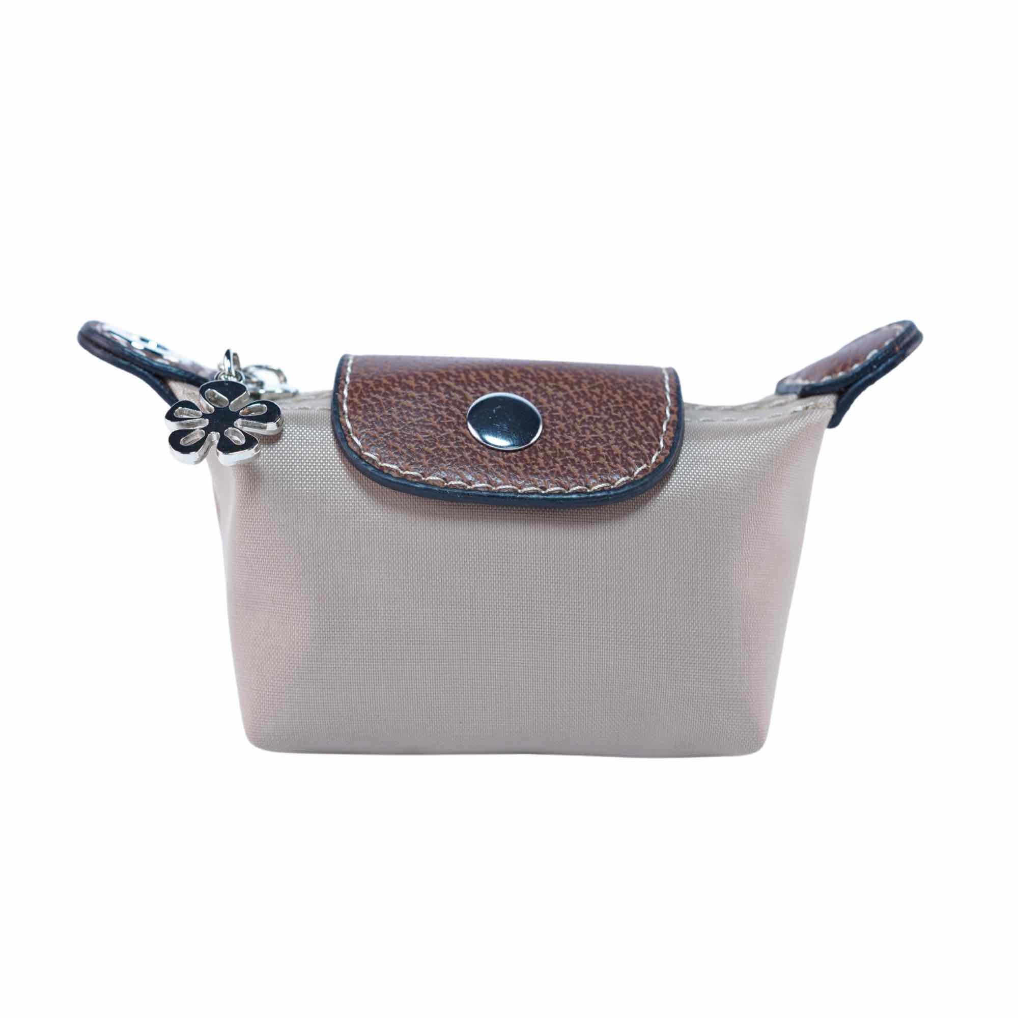 Small brown dog waste bag pouch with brown leather flap and flower charm on a white background.