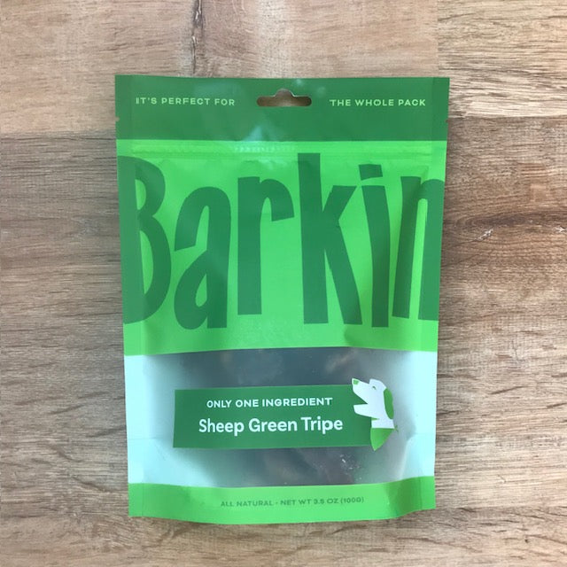 Green pouch of sheep green tripe Barkin' dog treats on wood table.