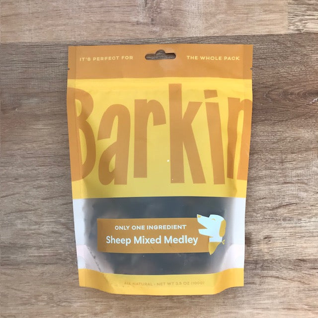 Yellow pouch of sheep mixed medley Barkin' dog treats on a wood table.