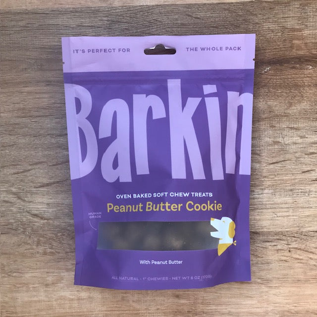 Purple pouch of Barkin' peanut butter cookie dog treats on wood table.