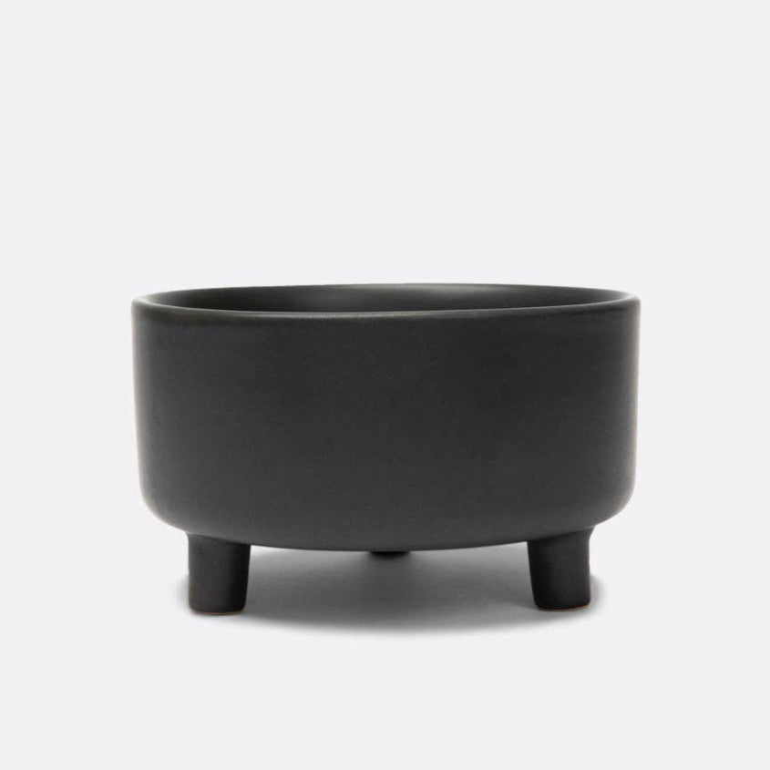 A black, three-legged, elevated, ceramic dog bowl on a white background.