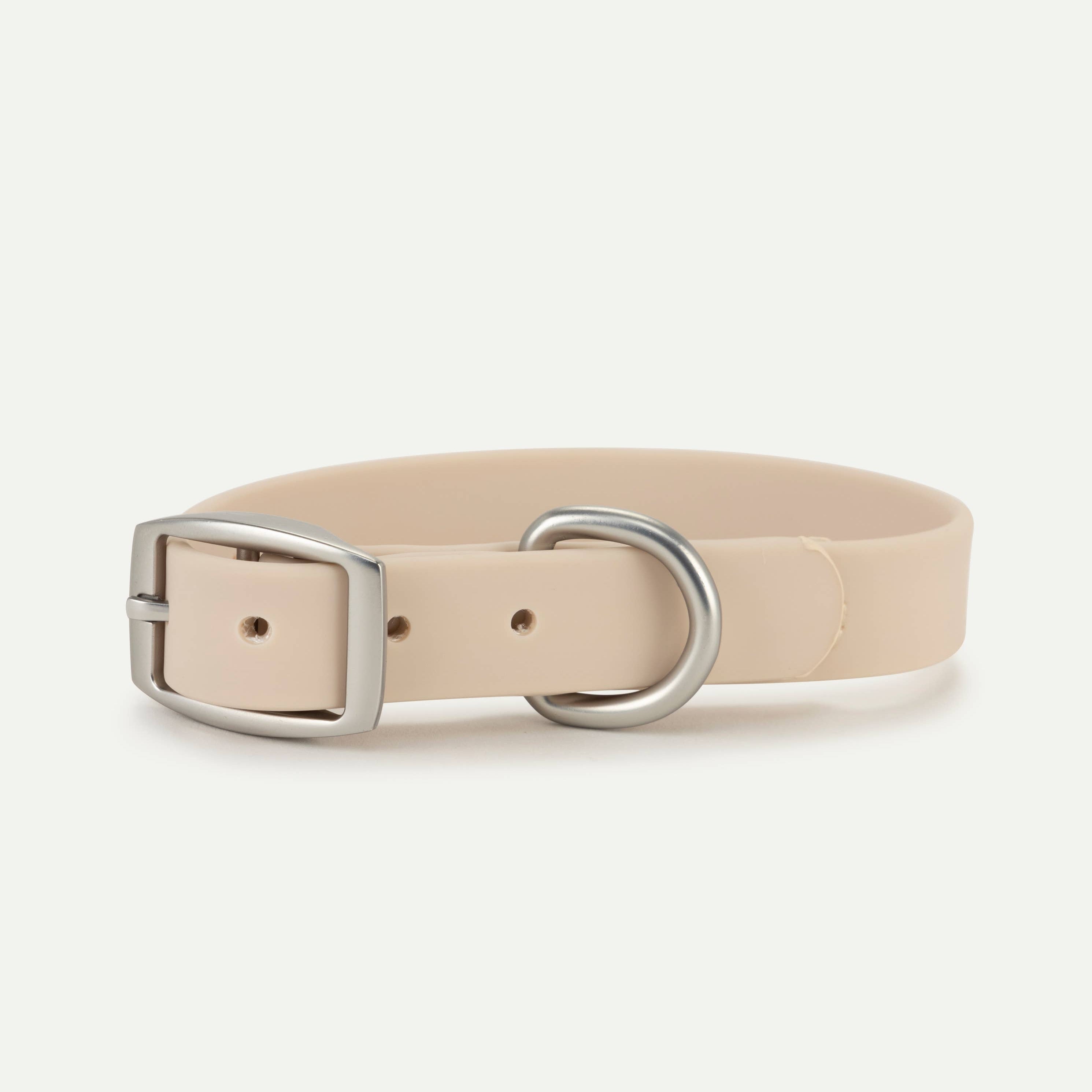 A sand-colored dog collar with silver hardware on a white background.