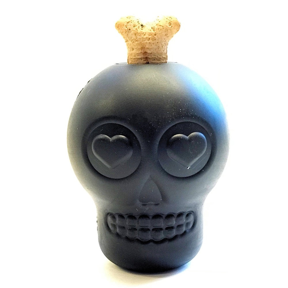 A black skull-shaped chew toy with a bone shaped dog treat sticking out of the top.