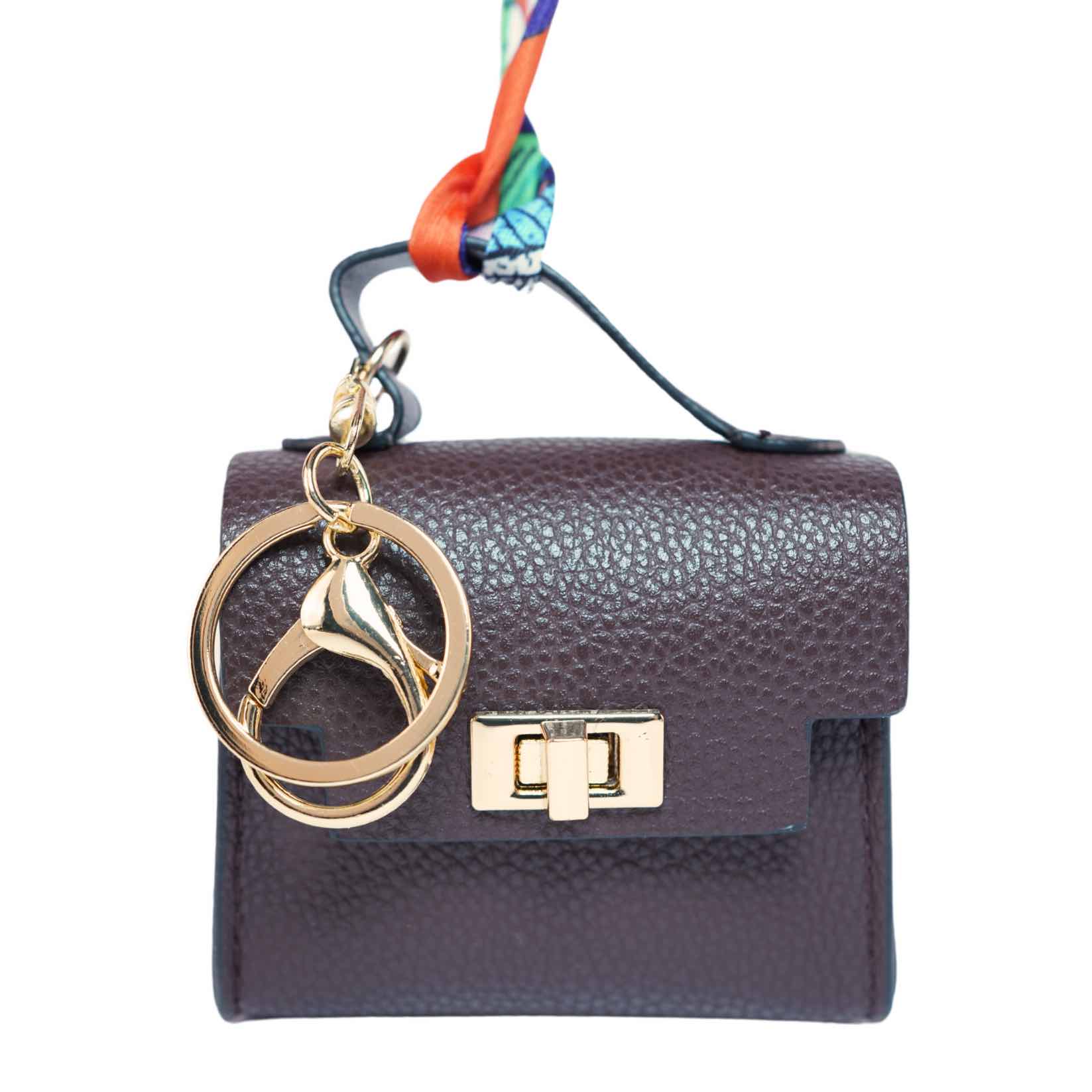 Brown handbag-themed dog poop bag dispenser with a keychain on a white background.