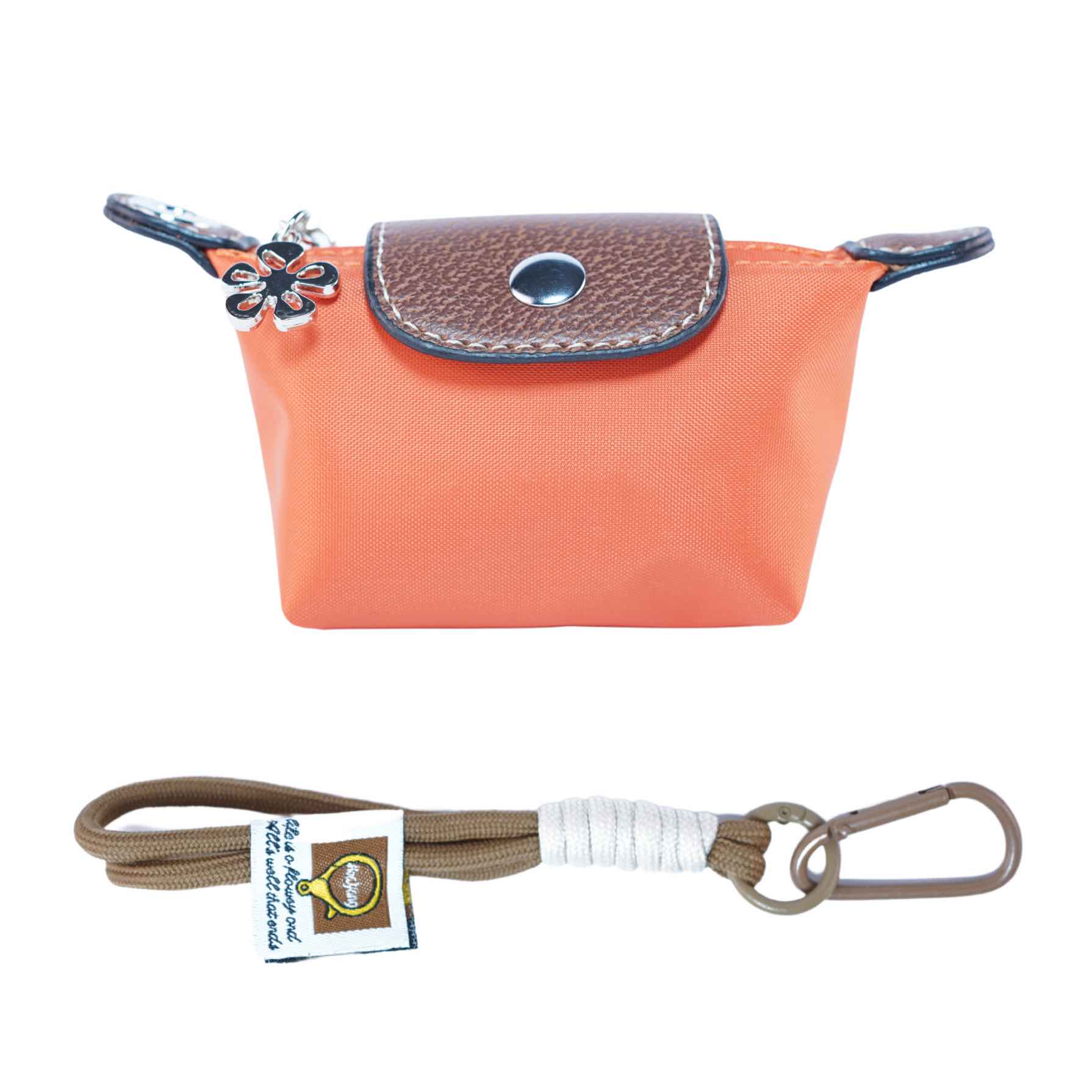 Small orange dog waste bag pouch with brown leather flap and strap with carabiner on a white background.