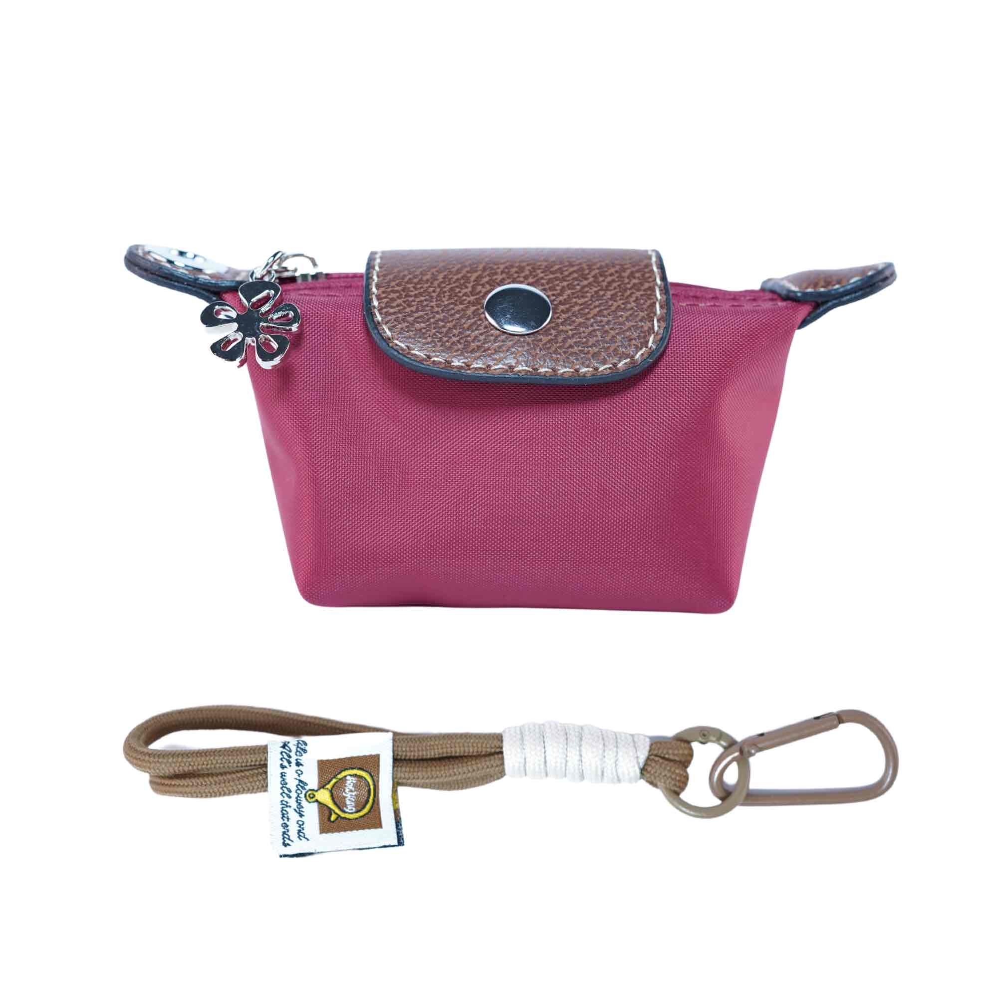 Small red dog waste bag pouch with brown leather flap and strap with carabiner on a white background.