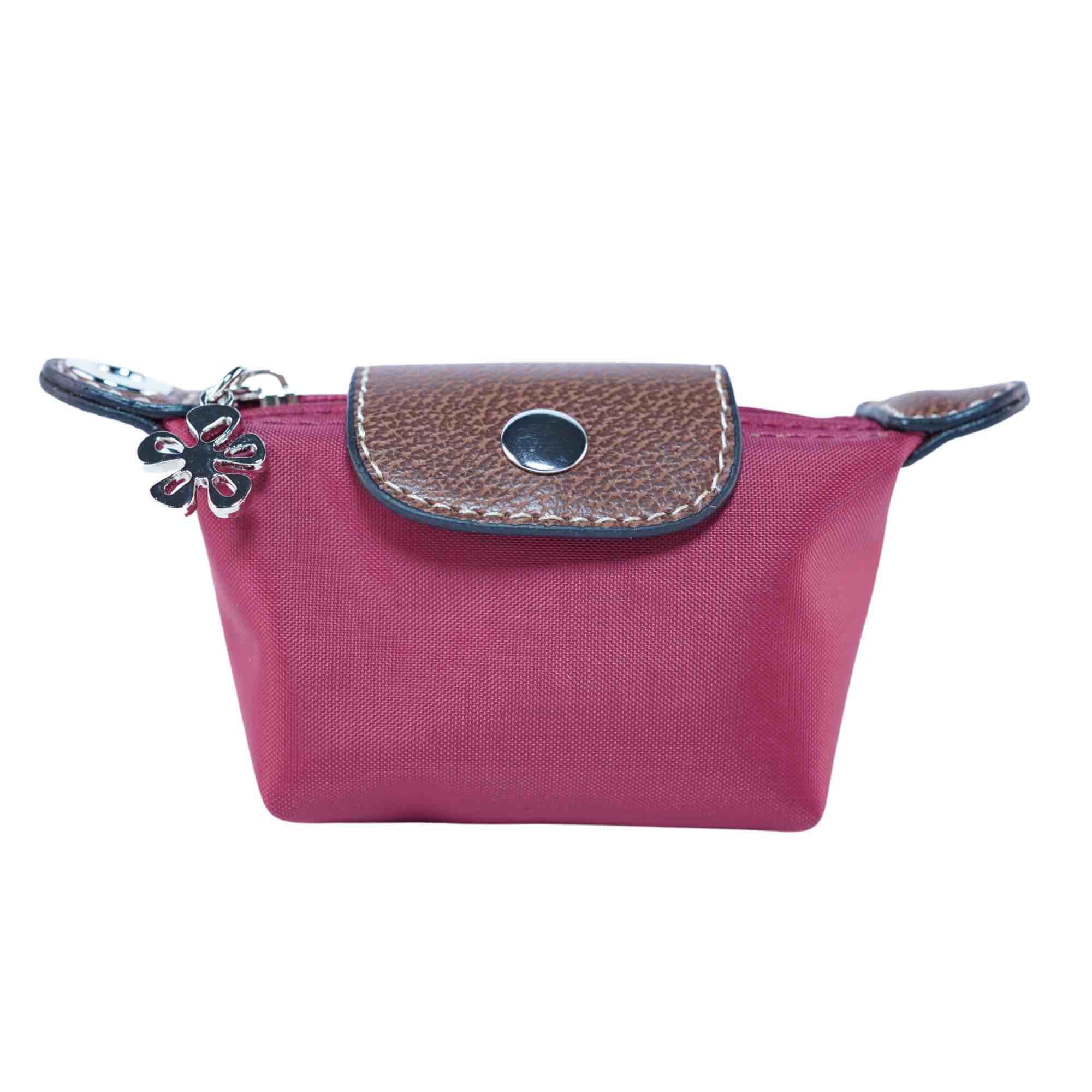 Small red dog waste bag pouch with brown leather flap and flower charm on a white background.